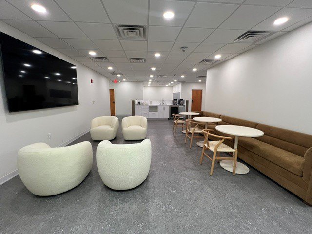 The lounge with a wall-mounted TV, bouclé chairs and café tables